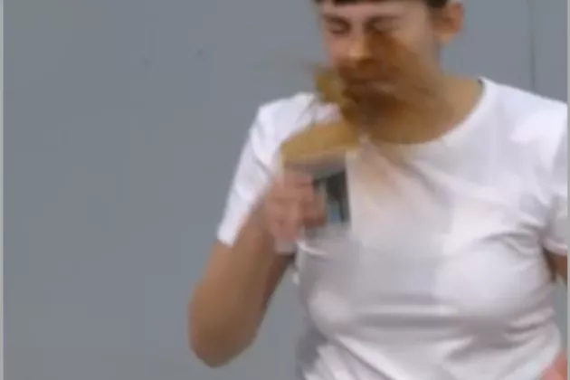 Foto: halvfigurbild på en kvinna i vit t-shirt som spiller kaffe i ansiktet.