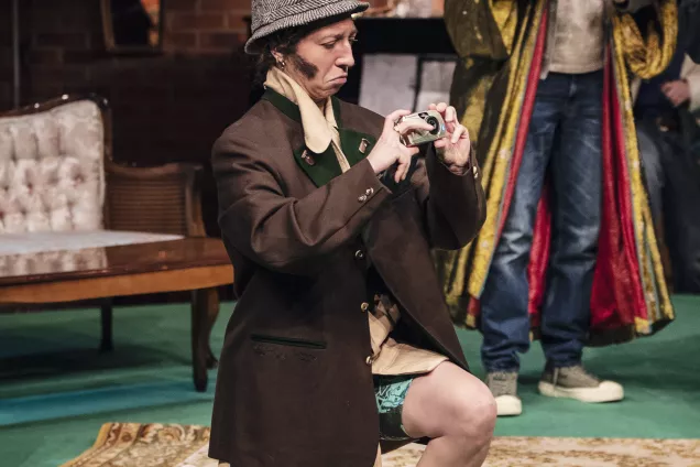 Person i hatt sitter på knä och fotar med en äldre kamera