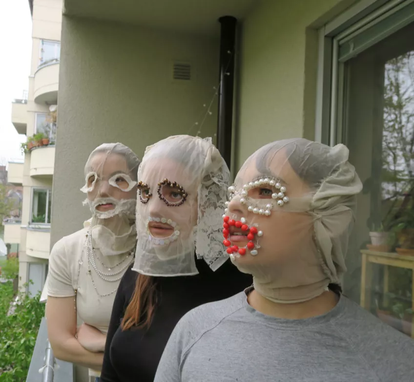 Tre konstnärligt maskerade personer på en balkong. Eventbild De kom och de gick TTP B 2021. Foto