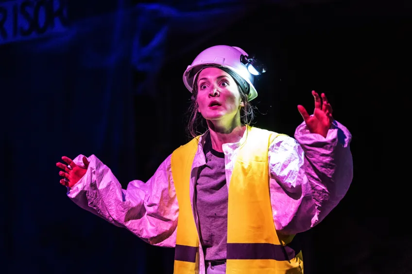 person i varselväst och hjälm i lila ljus